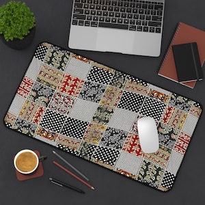 Peut inclure: Tapis de souris rectangulaire avec un motif patchwork. Le design présente des carrés avec des rayures, des pois et des motifs floraux en rouge, noir et blanc. Une souris d'ordinateur blanche est posée sur le tapis, avec un ordinateur portable et un carnet en arrière-plan.