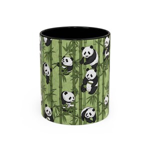 May include: A cylindrical ceramic mug with a black interior, decorated with a pattern of pandas amongst green bamboo. The pandas are black and white. The mug is suitable for hot or cold drinks.