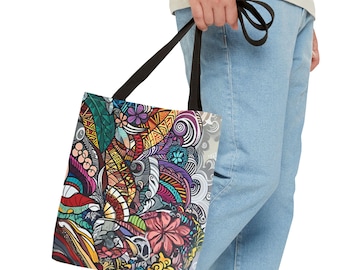 May include: A colorful tote bag with a black strap. The bag features a vibrant, intricate design with flowers, leaves, and abstract patterns in shades of red, orange, yellow, green, blue, and purple. The bag is held by a person wearing blue jeans.