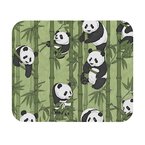 May include: A rectangular mouse mat with a repeating pattern of black and white pandas amongst green bamboo. The pandas are in various poses, some climbing, others sitting, creating a playful and nature-inspired design.