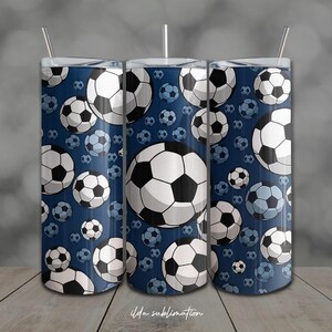 Puede incluir: Tres vasos de acero inoxidable con un estampado de balón de fútbol sobre un fondo azul marino. El diseño presenta balones de fútbol blancos y negros de varios tamaños. Cada vaso tiene una tapa plateada y una pajita. El texto "ilda sublimation" está en la parte inferior.