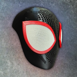 May include: A black and red 3D printed Spider-Man mask with a white mesh eye piece.