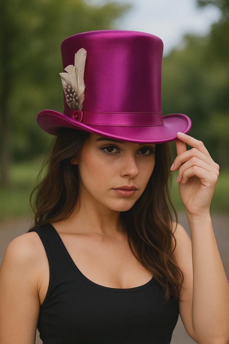 Pode incluir: Um chap&eacute;u de copa magenta com acabamento acetinado e pena decorativa. O chap&eacute;u tem aba larga e copa cil&iacute;ndrica. &Eacute; um acess&oacute;rio de moda.