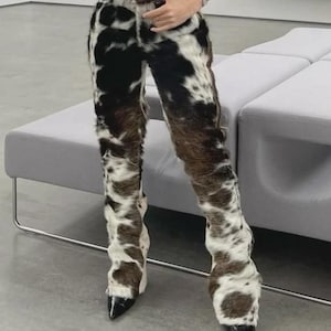 Peut inclure: Pantalon &agrave; motif de peau de vache avec une ceinture en cuir marron. Le pantalon pr&eacute;sente un motif tachet&eacute; noir, blanc et marron. Le pantalon a une texture unique et est associ&eacute; &agrave; des chaussures noires &agrave; bout pointu.
