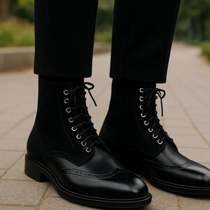May include: Black leather ankle boots with a lace-up design and brogue detailing. The boots have a suede panel at the top and are worn with black trousers. The boots have a low heel.