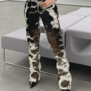 Peut inclure: Pantalon &agrave; motif de peau de vache avec une ceinture en cuir marron et des talons noirs &agrave; bout pointu. Le pantalon pr&eacute;sente un design unique avec des taches noires, marron et blanches, cr&eacute;ant un look distinctif.