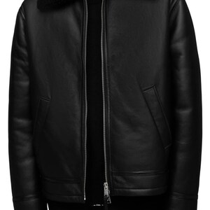 K&ouml;nnte beinhalten: Schwarze Lederjacke mit Shearling-Kragen und -Futter. Die Jacke hat einen Rei&szlig;verschluss vorne, zwei Seitentaschen und Shearling-Besatz an den Manschetten. Ein klassischer Stil, geeignet f&uuml;r kaltes Wetter.