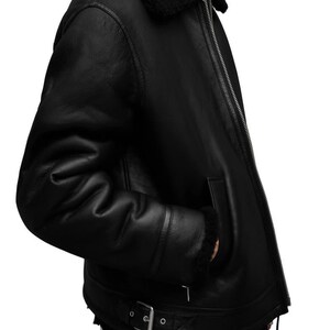 K&ouml;nnte beinhalten: Schwarze Lederjacke mit Shearling-Kragen und -Futter. Die Jacke hat einen Rei&szlig;verschluss, Seitentaschen und einen Schnallenriemen an der Taille. Ein klassisches Oberbekleidungsst&uuml;ck.