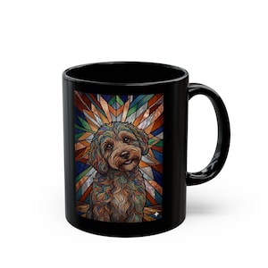May include: Black ceramic mug featuring a colorful illustration of a dog with a stained-glass style background. The dog has brown fur and is smiling. The mug is a standard size for coffee or tea.