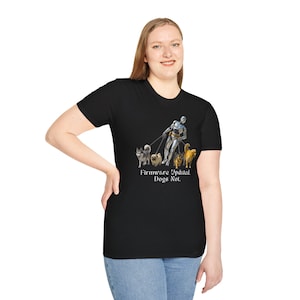 Puede incluir: Camiseta negra con un gráfico de un robot paseando perros con correas. El texto "Firmware Updated. Dogs Not." está impreso debajo del gráfico. La camiseta está hecha de un material suave.