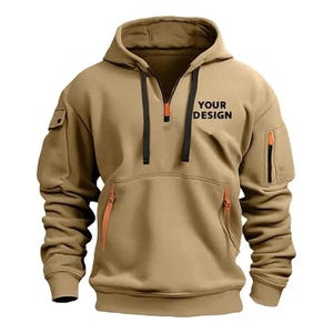 May include: A tan hooded sweatshirt with a half-zip closure and multiple pockets. The sweatshirt features black drawstrings and orange zipper accents. The text "YOUR DESIGN" is printed on the chest. This casual outerwear is suitable for various activities.