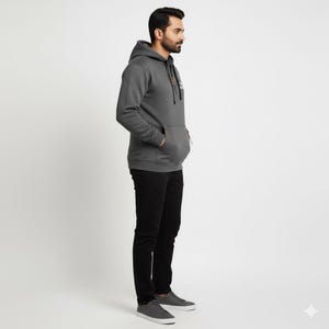 May include: A charcoal gray hoodie with a drawstring hood and a kangaroo pocket. The hoodie has a small logo on the chest and a zipper detail on the pocket. The person is wearing black pants and gray sneakers.