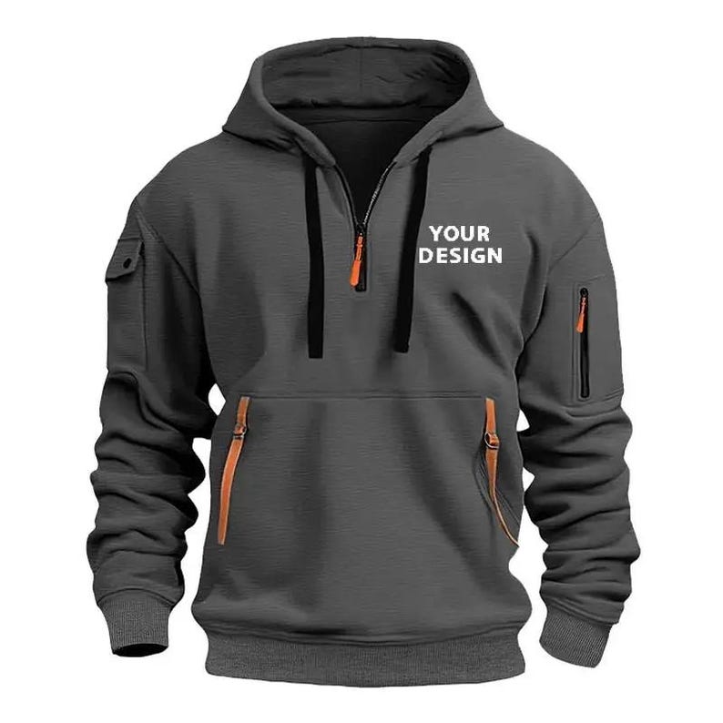 Personalised Logo Hoodies, Custom Logo Hoodie, Company Merch Jumpers, Custom Workwear Gift for Worker, Uniform Hoodie, Gift for Dad. May include: A charcoal gray hoodie with a drawstring hood and a half-zip Customizable hoodie in black. Available in different colors and personalized sizes closure. The hoodie features a kangaroo pocket, a small pocket on the left sleeve, and two zippered pockets. The text "YOUR DESIGN" is printed on the chest. The zipper pulls and pocket accents are orange.