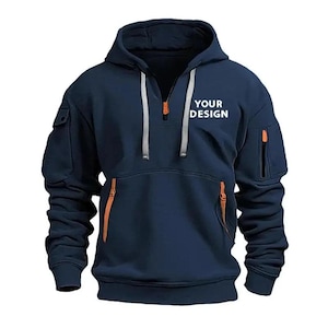 May include: Navy blue hooded sweatshirt with a half-zip closure and orange zipper accents. Features a kangaroo pocket and two zippered pockets on the sleeves. The text "YOUR DESIGN" is printed on the chest.