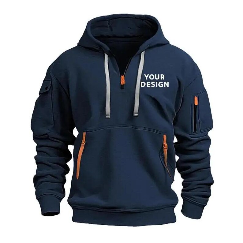May include: Navy blue hooded sweatshirt with a half-zip closure and orange zipper accents. Features a kangaroo pocket and two zippered pockets on the sleeves. The text "YOUR DESIGN" is printed on the chest.