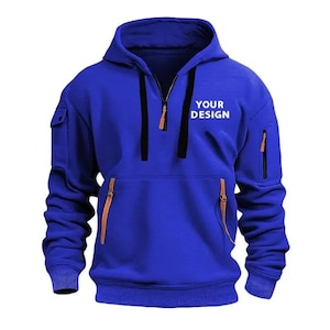 May include: A royal blue hoodie with a half-zip closure, a hood, and two side pockets with zippers. The text "YOUR DESIGN" is printed on the front. The hoodie has a kangaroo pocket and ribbed cuffs.