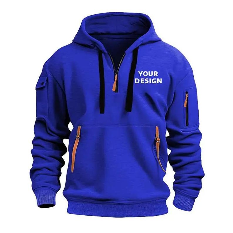 May include: A royal blue hoodie with a half-zip closure, a hood, and two side pockets with zippers. The text "YOUR DESIGN" is printed on the front. The hoodie has a kangaroo pocket and ribbed cuffs.