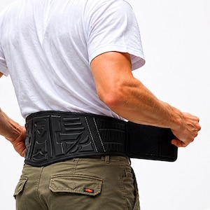 May include: A black lumbar support belt featuring a molded, textured back panel with geometric patterns and a wide, adjustable hook-and-loop closure strap. The belt is constructed from durable fabric with reinforced stitching along the edges.