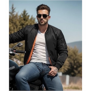 May include: A black bomber jacket with a bright orange lining, worn over a plain white t-shirt and blue denim jeans. The jacket features a ribbed collar, ribbed cuffs, and a zippered utility pocket on the left sleeve. Dark sunglasses are worn.