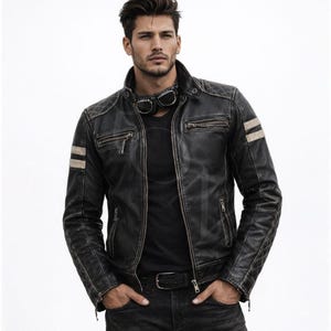 May include: A black leather jacket featuring a stand-up collar, quilted shoulder and elbow panels, and two horizontal light-colored stripes on each sleeve. The jacket includes a front zipper closure, two chest zipper pockets, and two side pockets.