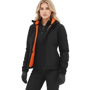 May include: Black softshell jacket with an orange interior lining, a hood, and a zipper closure. The jacket is worn with black gloves and pants. This outerwear is designed for cold weather and outdoor activities.