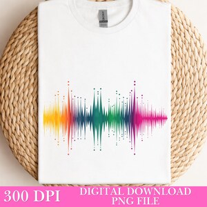Op de afbeelding: Wit T-shirt met een kleurrijk geluidsgolfontwerp, dat overgaat van geel naar paars. De tekst "300 DPI DIGITAL DOWNLOAD PNG FILE" staat onderaan. Het T-shirt wordt gepresenteerd op een geweven achtergrond. Het Gildan-logo is zichtbaar.