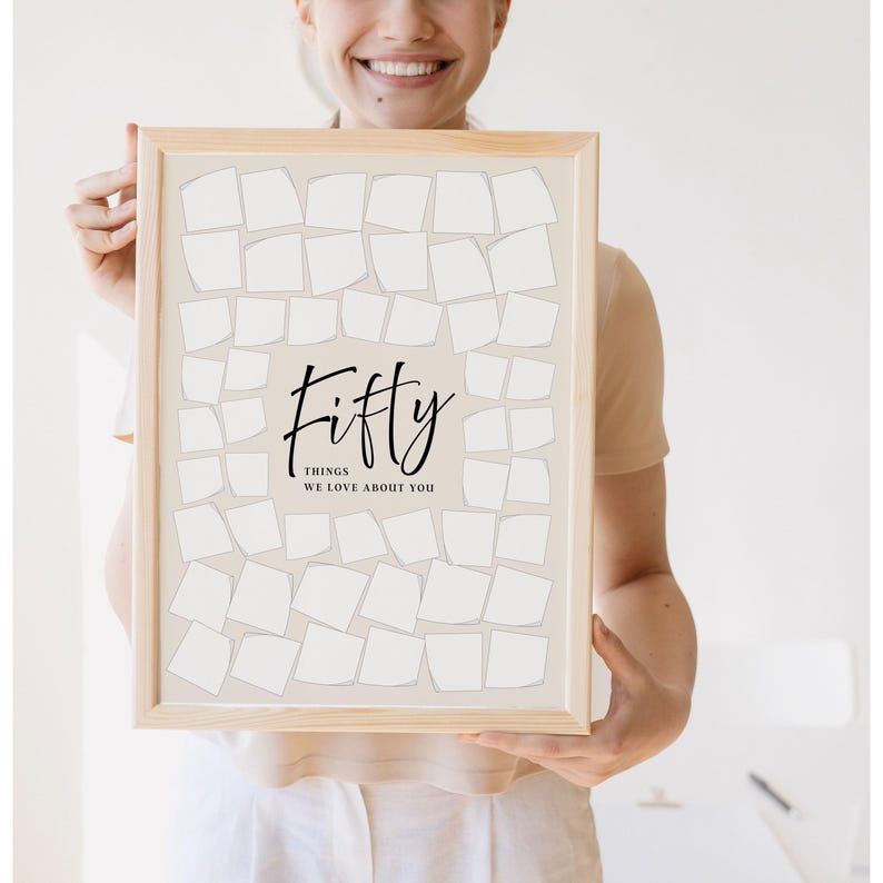 May include: A framed print with the word "Fifty" in elegant script, with the text "THINGS WE LOVE ABOUT YOU" below. The print features a grid of blank, off-white shapes on a light beige background, perfect for personalized notes.