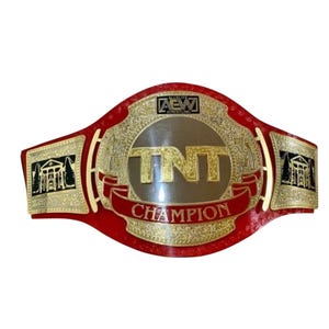 May include: A red championship wrestling belt featuring a large central gold plate with the text TNT CHAMPION and the AEW logo at the top. The belt includes two side gold plates depicting a building with columns and trees on a black background.