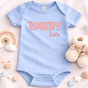 May include: A white ceramic mug with a black handle and the text "But First, Coffee" in a bold, black font. The mug is set against a blurred background, suggesting a cozy setting.