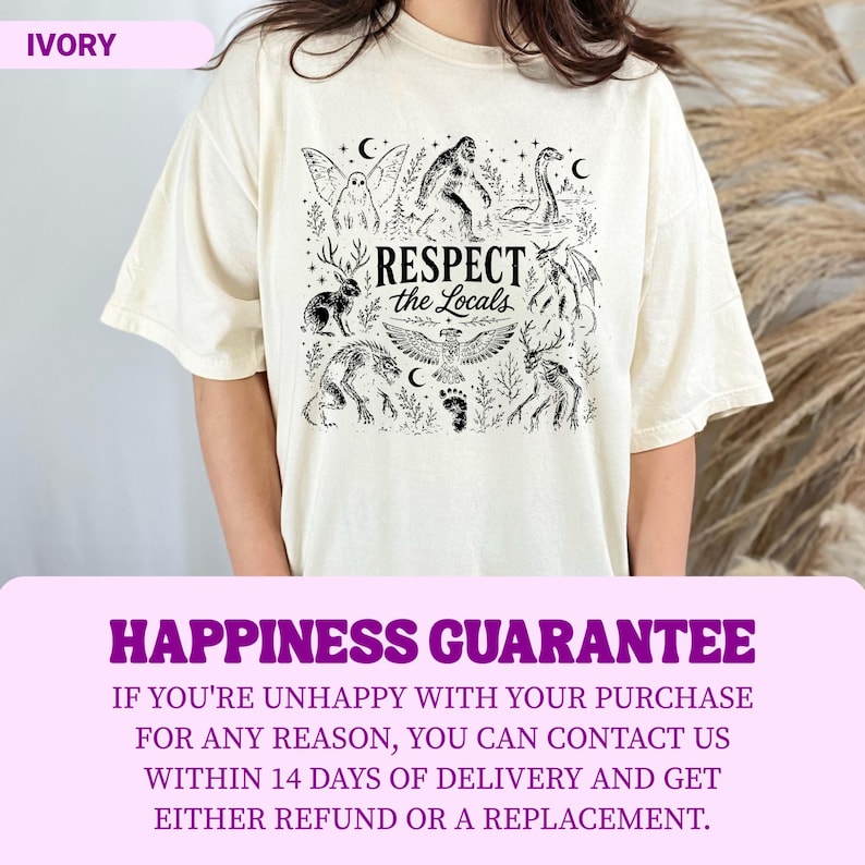 May include: An ivory short-sleeve t-shirt featuring a black graphic print of various mythical creatures including Bigfoot, a mothman, and a jackalope. The central text reads "RESPECT the Locals" surrounded by stars, moons, and forest elements.
