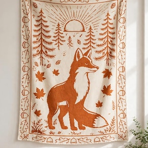 Peut inclure: Une tapisserie murale tissée de couleur crème représentant un grand renard orange brûlé au centre, entouré de pins, d'un soleil et de feuilles d'érable tombantes. La bordure est ornée d'un motif répétitif de glands et de feuilles de chêne.