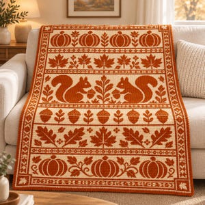 May include: A rectangular crochet blanket featuring a repeating autumn-themed pattern in burnt orange and cream. The design includes rows of pumpkins, maple leaves, squirrels holding acorns, and individual acorns arranged in horizontal bands.