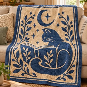 Peut inclure: Une couverture en crochet rectangulaire présentant un motif bicolore bleu et crème. Le centre affiche un chat lisant un livre ouvert, entouré d'un croissant de lune, d'étoiles et de bordures de vignes feuillues. Le motif est uniforme.
