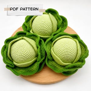 Op de afbeelding: Drie gehaakte koolkoppen met lichtgroene centra en donkergroene buitenbladeren met een getextureerd, gelaagd uiterlijk. De tekst PDF PATTERN is zichtbaar bovenaan de afbeelding, wat wijst op een digitaal document voor dit handwerk.