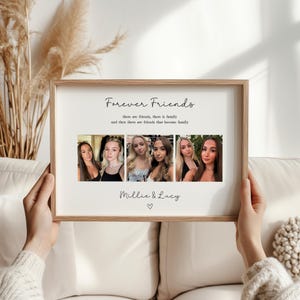 May include: A framed print with the text "Forever Friends" and a series of six photographs. The print includes the names "Millie & Lucy" and a heart symbol. The frame is a light brown color.