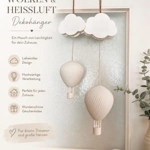 Op de afbeelding: Twee witte hangende decoraties met wolken die aan bruin touw boven twee gestructureerde heteluchtballonmanden hangen. De tekst luidt WOLKEN & HEISSLUFT Dekohänger, Ein Hauch von Leichtigkeit für dein Zuhause, Liebesvolles Design, Hochwertige Verarbeitung, Perfekt für jedes Zuhause, Wunderschöne Geschenkidee, Für kleine Träumer und große Herzen, HANDGEMACHT MIT LIEBE FÜR DICH.