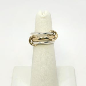 Könnte beinhalten: Ein Set aus drei Keramikbechern mit gesprenkelter, matter Oberfläche. Die Becher sind in Creme-, Hellgrau- und Dunkelgrautönen gehalten. Jeder Becher hat ein schlichtes, minimalistisches Design.