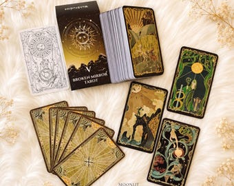 May include: A deck of Broken Mirror Tarot cards with a black box featuring a gold sun illustration. The set includes a stack of cards, several fanned-out cards with gold sunburst patterns, and three individual cards displaying detailed illustrations.