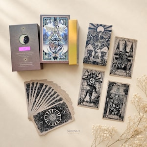 Könnte beinhalten: Ein Tarot-Deck mit dem Titel Whisper of Finale, bestehend aus einer Schachtel mit Mondmotiv, einer goldgeränderten Kartenbox, einer Anleitung und mehreren Karten mit detaillierten schwarz-weißen Illustrationen wie The Fool und The Magician.