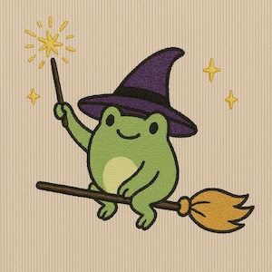 May include: A whimsical illustration of a green frog wearing a purple witch hat, riding a broom, and holding a wand with a starburst. The frog is smiling, and there are yellow stars in the background. The design is on a beige, textured background.