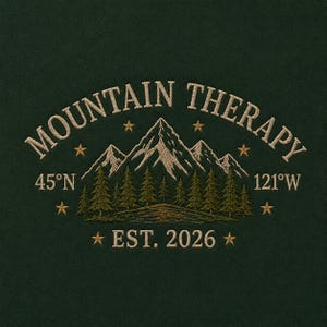 May include: Dark green embroidered design with the words "MOUNTAIN THERAPY" above a mountain range and pine trees. The design includes the text "45°N" and "121°W", with "EST. 2026" below. The design is accented with small gold stars.