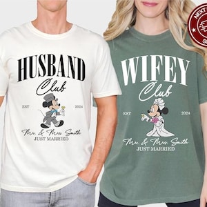 May include: Two matching t-shirts, one white and one green, with the phrases "HUSBAND Club" and "WIFEY Club" in bold, curved text. Each shirt has a cartoon mouse character dressed for a wedding, with the text "Mr. & Mrs. Smith JUST MARRIED".
