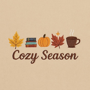 May include: Embroidered design featuring autumn elements: a yellow leaf, books, an orange pumpkin, a red leaf, and a brown mug with steam. The words "Cozy Season" are written in brown script below the illustrations.