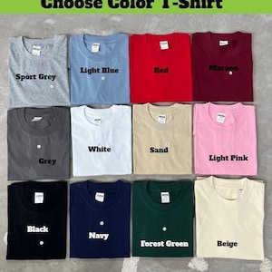 Puede incluir: Una selecci&oacute;n de camisetas plegadas en varios colores, incluyendo gris deportivo, azul claro, rojo y granate. El texto "Choose Color T-Shirt" est&aacute; en la parte superior. Otros colores incluyen gris, blanco, arena, rosa claro, negro, azul marino, verde bosque y beige.