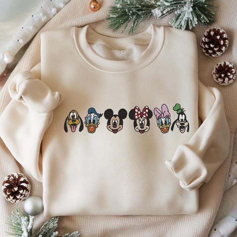 Puede incluir: Sudadera color crema con caras bordadas de personajes de dibujos animados: Pluto, Pato Donald, Mickey Mouse, Minnie Mouse, Daisy Duck y Goofy. La sudadera tiene cuello redondo y mangas largas, ideal para uso casual.