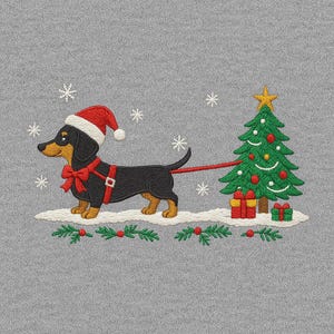 May include: Embroidered design of a black and tan dachshund wearing a Santa hat and pulling a Christmas tree. The dog has a red bow and harness. Snowflakes and gifts complete the festive scene on a gray background.