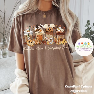 May include: Espresso-coloured t-shirt with a graphic of cartoon characters with pumpkin spice drinks and pumpkins. The text "Pumpkin Spice & Everything Nice" is below the graphic. The shirt is from Comfort Colors.