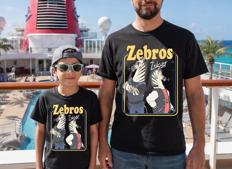 May include: Black t-shirts with the word "Zebros" in yellow, featuring a cartoon zebra design. The shirts are worn by a person and a child. The background includes a cruise ship and a pool.