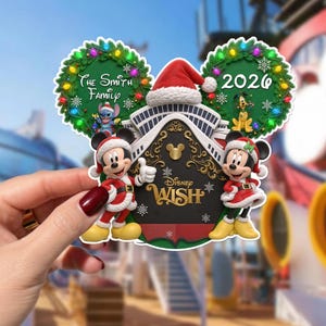 May include: A Disney Wish cruise ship ornament featuring Mickey and Minnie Mouse in Santa outfits, Stitch, and Pluto. The design includes two green wreaths with colourful lights, the text The Smith Family, 2026, and the Disney Wish logo.