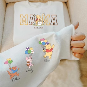 May include: White sweatshirt with the word "MAMA" in brown and gold block letters, with a Winnie the Pooh graphic. The sweatshirt also features the text "EST. 2026". A second white sweatshirt has cartoon characters holding balloons with the names Nathan, Emily, and Olivia.